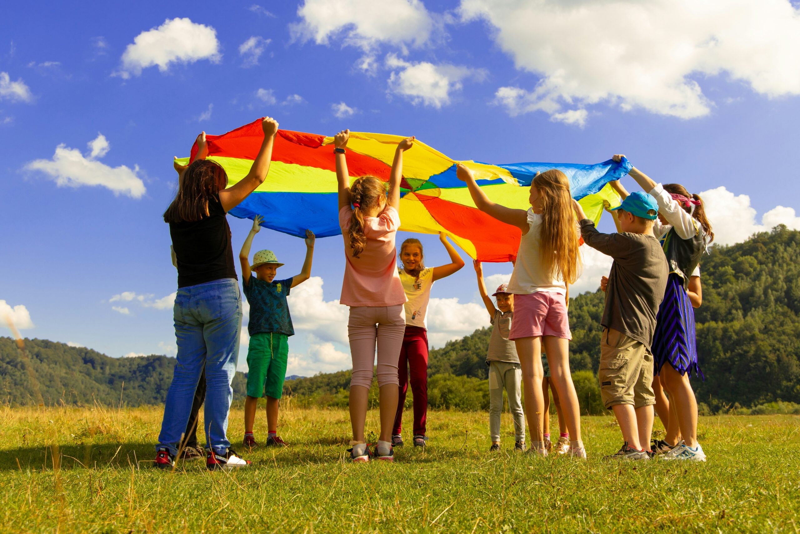 Kids playing with a parachute outside.