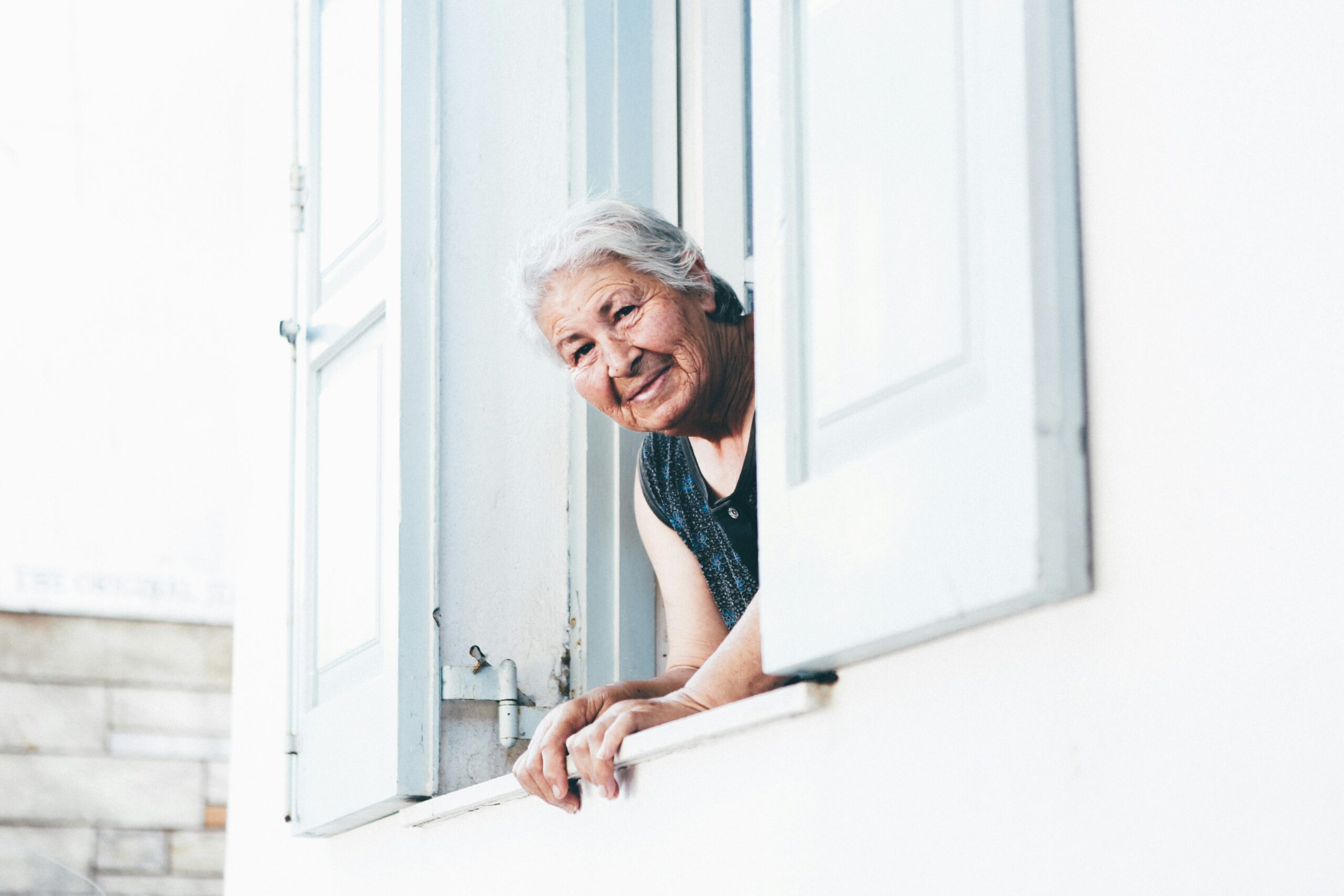An old woman looks out a window.