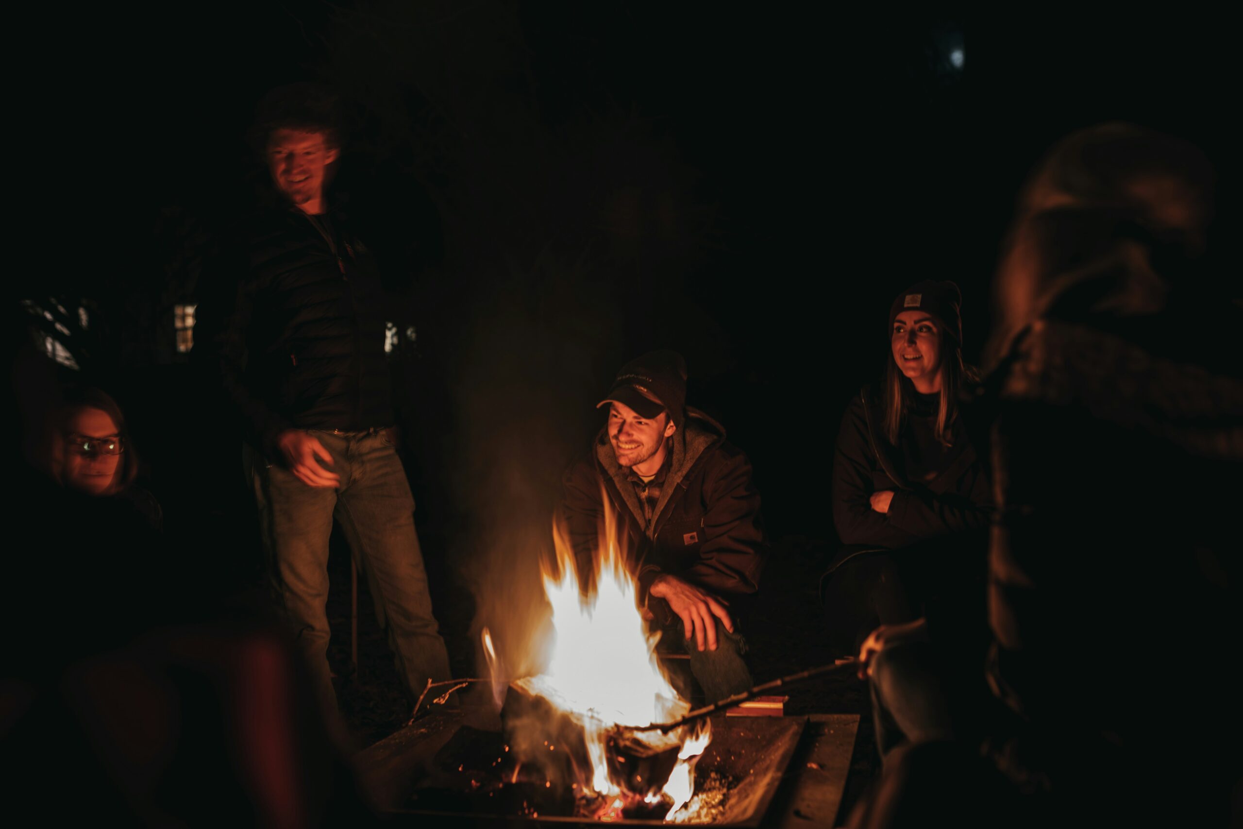 A family sits around a nighttime bonfire.