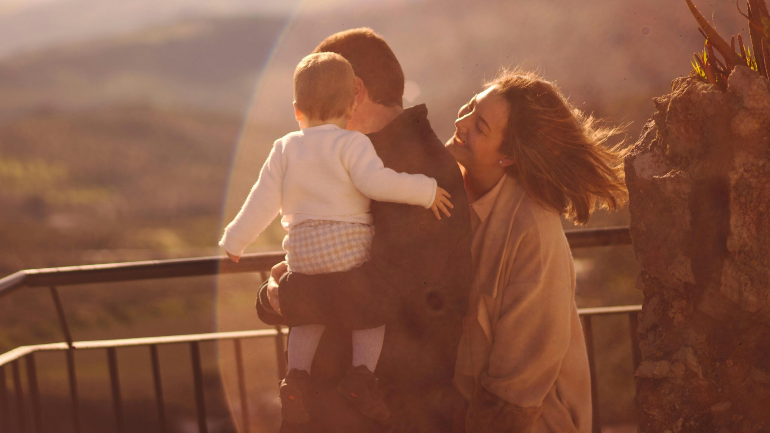 Parents and a baby look over a railing.
