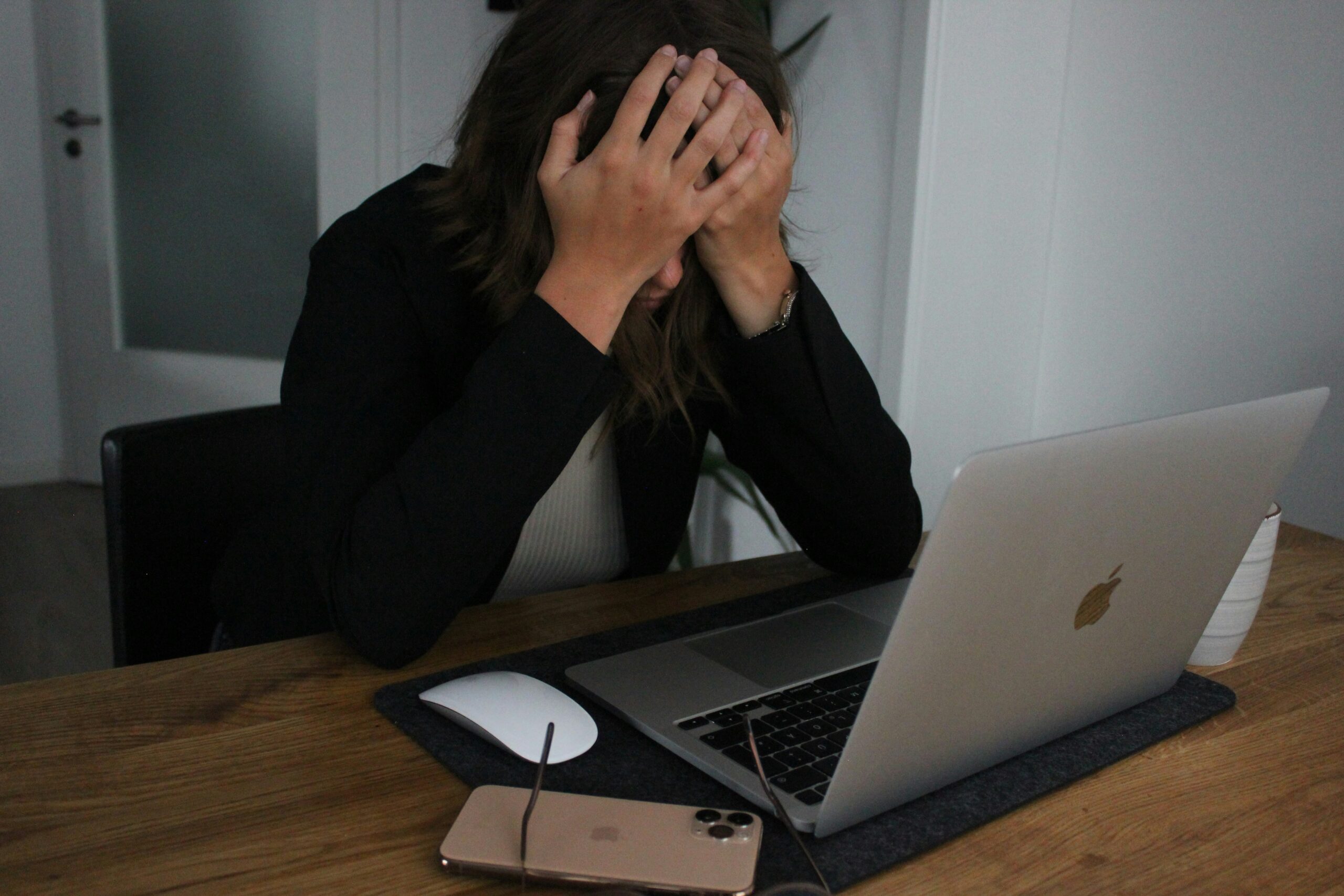 A woman at a laptop with her head in her hands.