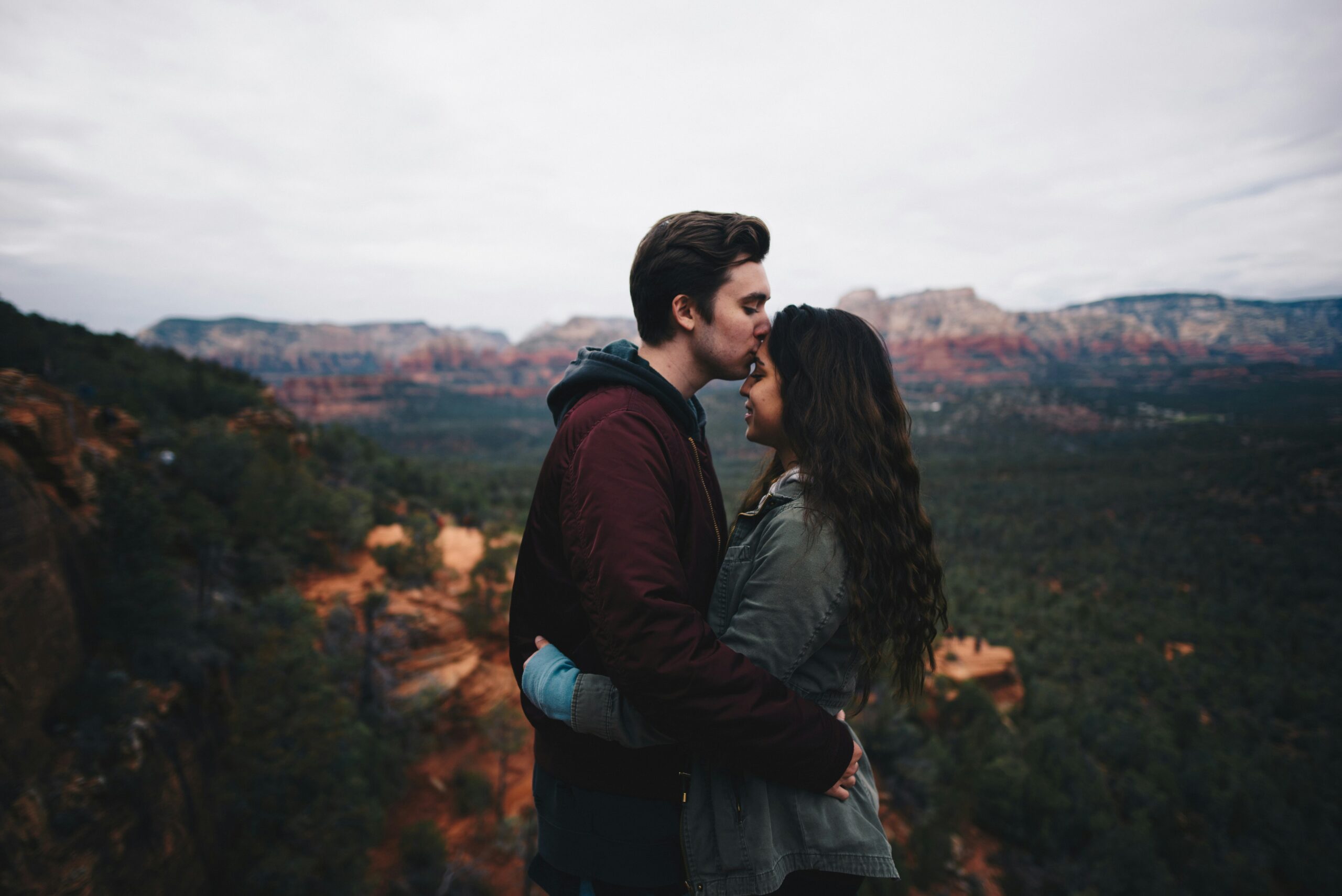 A man hugs a woman on top of a mountain.