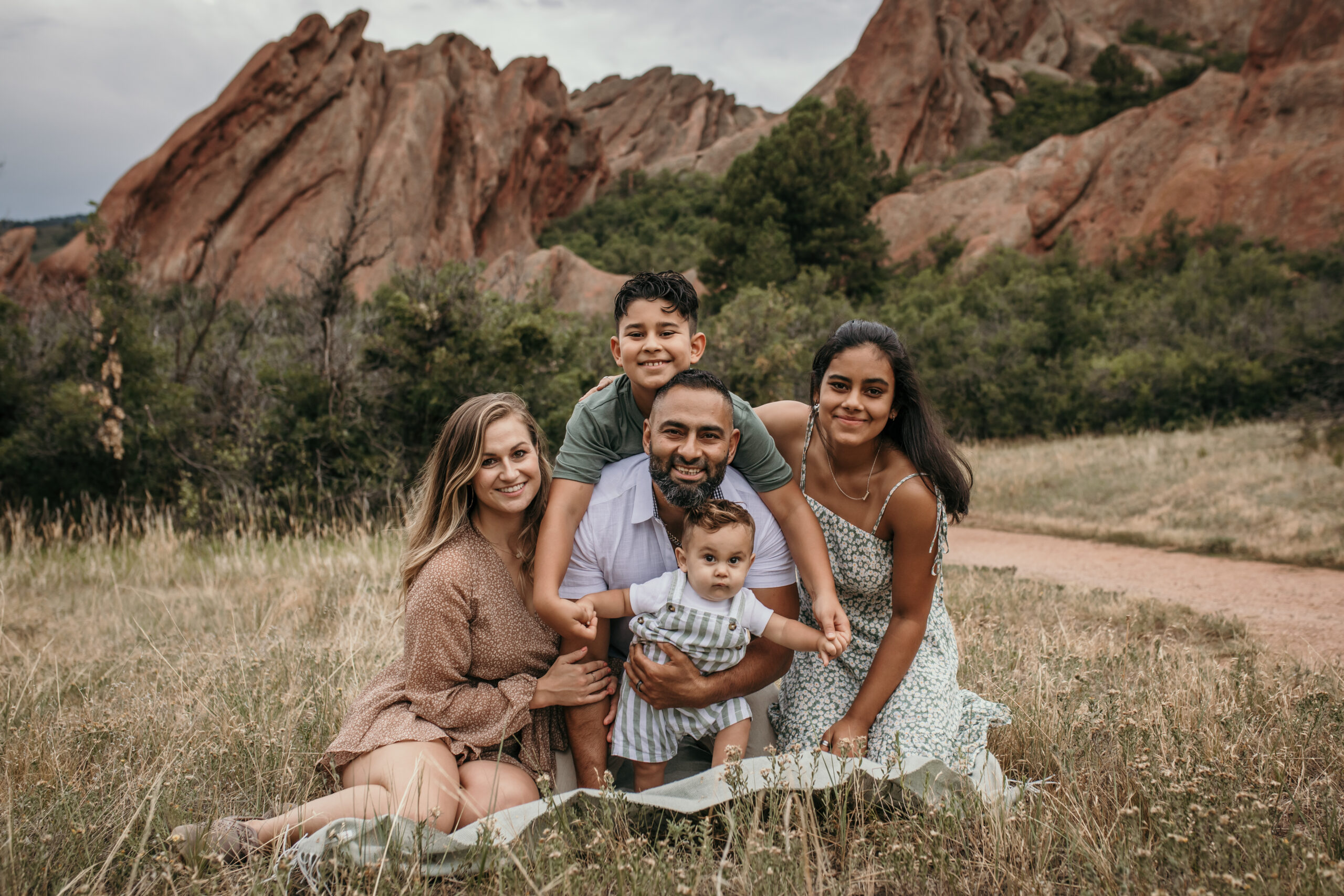 Kendra and her husband and kids sit in a field.