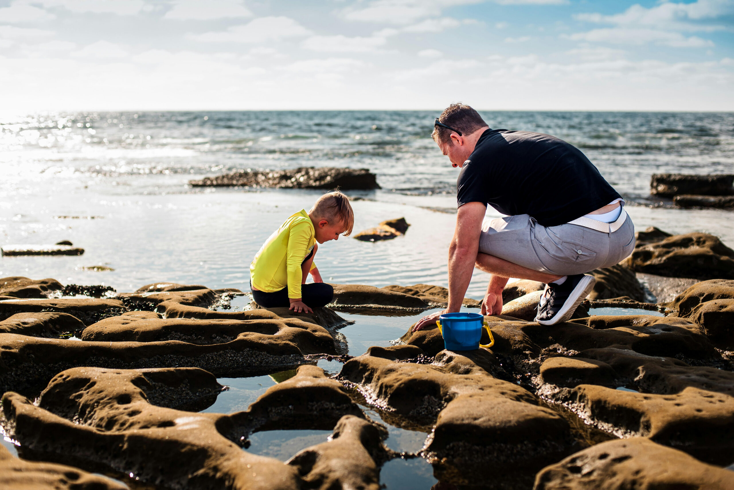 A dad and a young boy play near the beach.