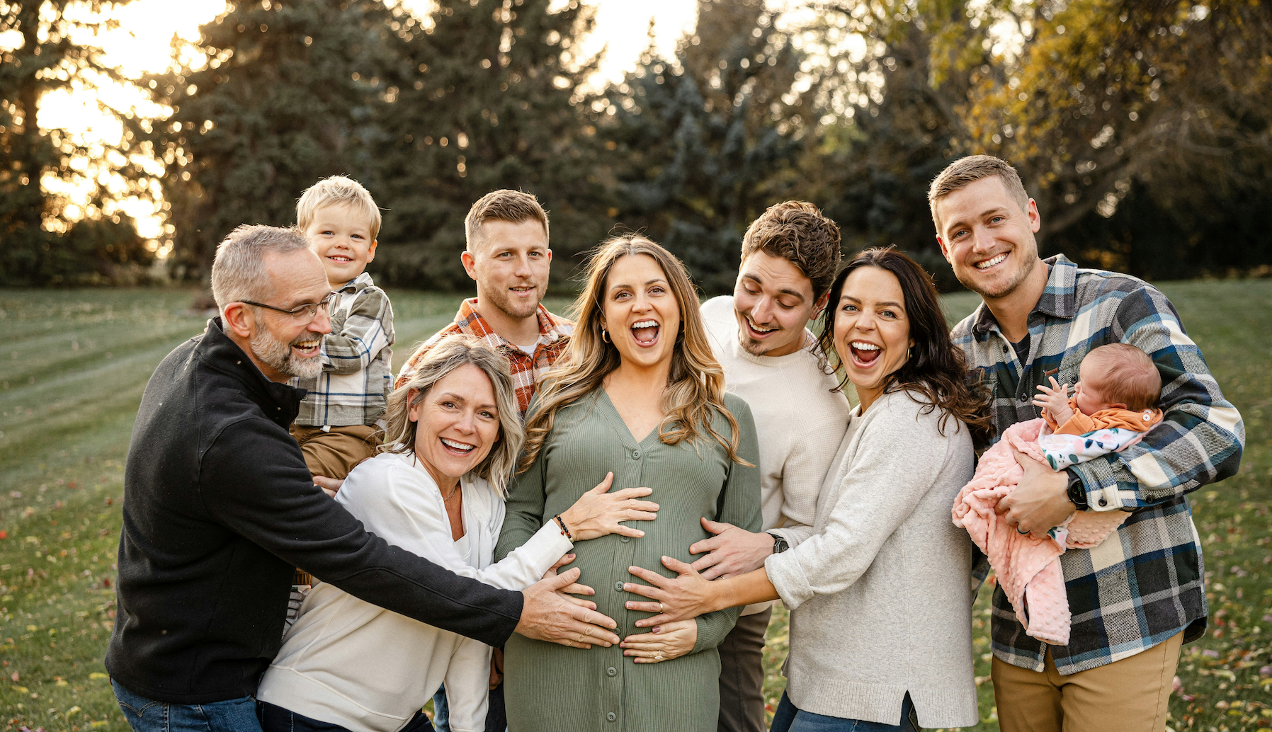 A family poses with a pregnant woman.