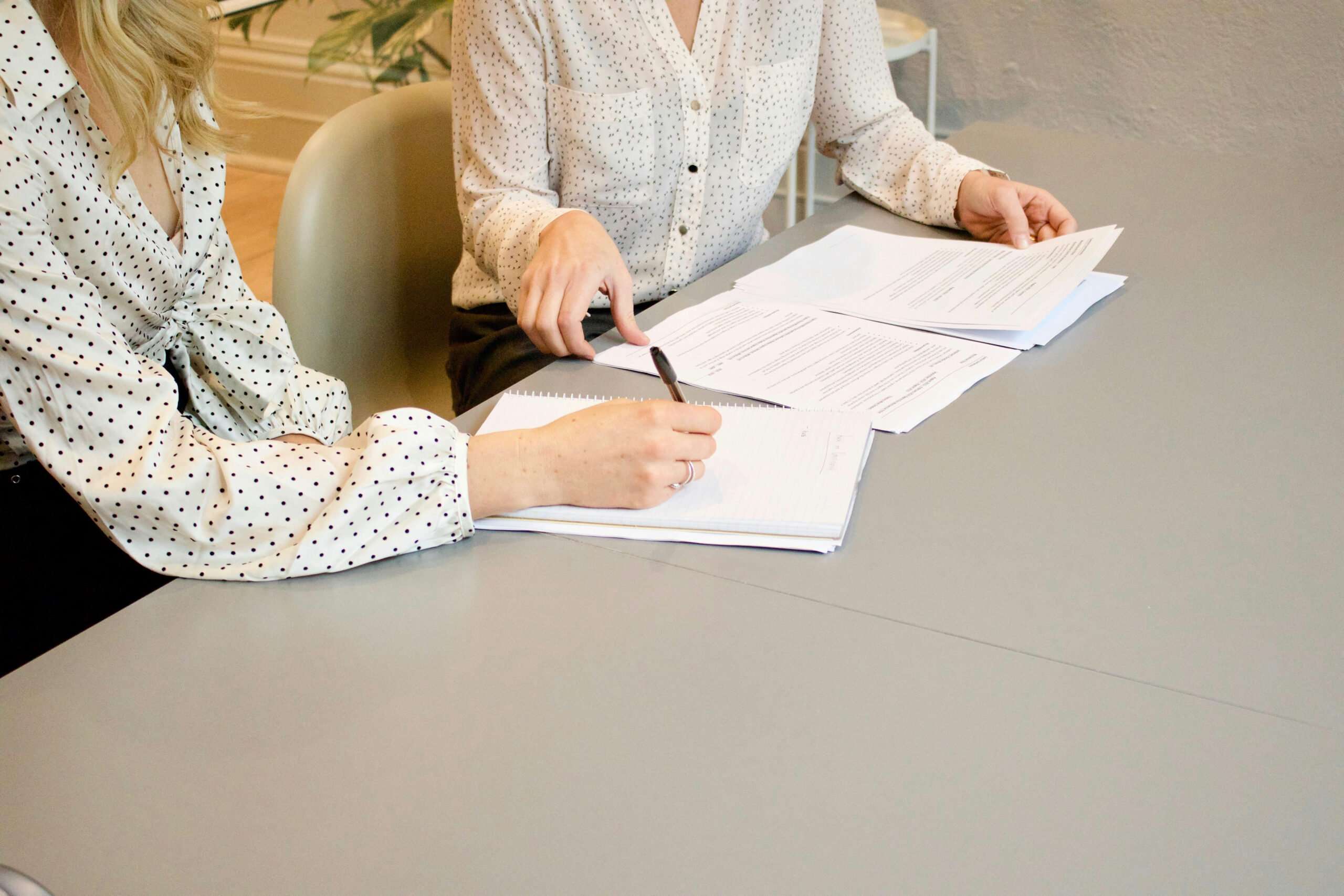 Two womans' hands sign papers.